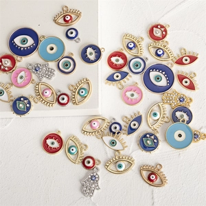 Detailed flat lay of assorted colorful enamel evil eye and Hamsa hand alloy charms with rhinestones