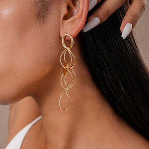 Close-up of model wearing gold layered geometric hoop earrings with a metallic finish