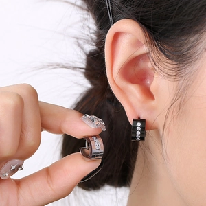 Detail of silver and black huggie hoop earrings with cubic zirconia inlay on ear