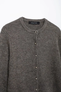 Detailaufnahme der Strickjacke mit silbernen Metallknöpfen und hochwertiger Stoffstruktur