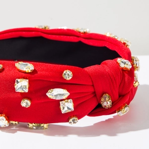 Détail d'un serre-tête noué rouge orné de strass étincelants montés sur métal doré