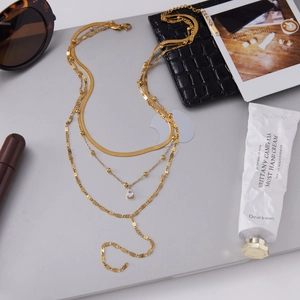 Flat lay of triple-layered 18K gold stainless steel necklaces with zircon drop pendant