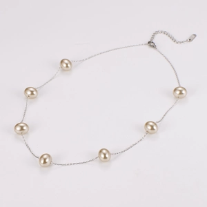 Detail of silver chain necklace with elegant light gold pearls and lobster clasp