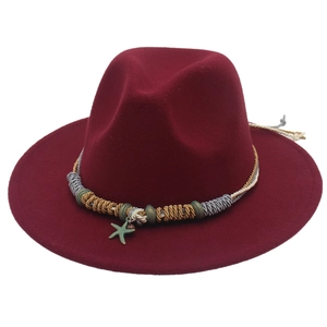 Dettaglio del cappello fedora bordeaux con ciondolo a stella e fascia in metallo
