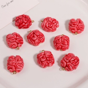 Macro shot of 9 red resin brain pendants on a white plate for DIY jewelry making
