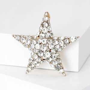 Close-up of gold star brooch with shimmering crystals on minimalist white background