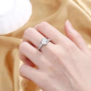 Detail of a sparkling silver zircon ring with six-prong setting on golden silk fabric