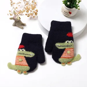 Close-up of knit kids mittens with green plush crocodile patch and soft winter texture