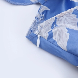 Detailed close-up of invisible zipper and blue floral print on backless summer dress