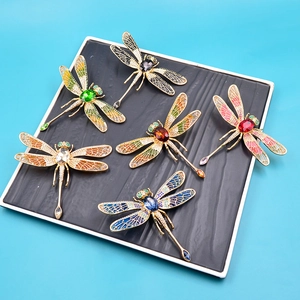Macro view of six colorful dragonfly brooches with enamel wings on a black display tray