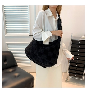 Model showcasing a large black plush tote bag with a trendy checkered texture design