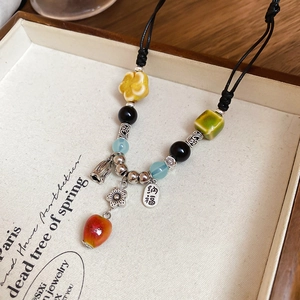 Close-up of vintage ceramic necklace with yellow flower bead and Na Fu engraved pendant