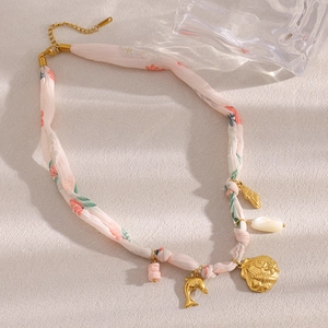 Detail view of 18K gold plated seashell and dolphin charms on a pink ribbon necklace
