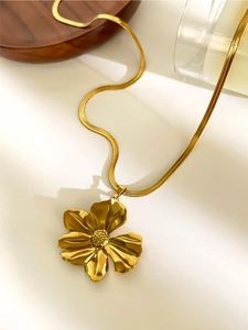 Detailed close-up of a gold floral pendant with 3D petals and a delicate snake bone chain