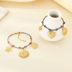 Bohemian colorful woven rope bracelet with gold sun and heart pendants on white ceramic