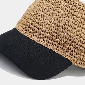Close-up of woven straw baseball cap with contrasting black brim and breathable texture