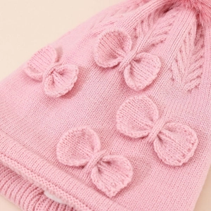 Pink knit winter hat for toddler girls with bow accent and faux fur pompom detailing