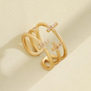 Macro detail of gold-plated triple-layer open ring featuring cross motifs and white crystals