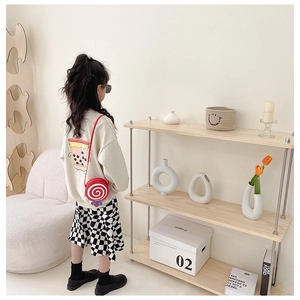 Detail of round red and white lollipop-shaped crossbody bag worn by a child in style