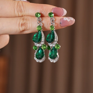 Detail of silver drop earrings with emerald gemstones and sparkling rhinestones