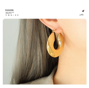 Macro detail of high-polished U-shaped gold earrings showing sleek geometric metallic curves