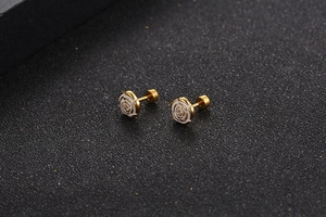 Macro shot of gold-plated titanium steel earrings with elegant white rose floral details