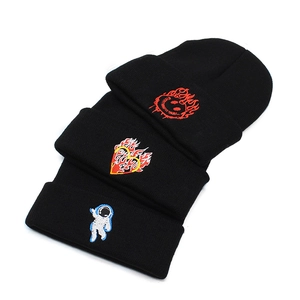 Three black knitted beanies with colorful embroidery of astronaut, heart, and smiley face
