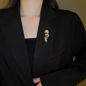Detailed view of the sparkling gold dragon brooch with crystal inlay on a black blazer