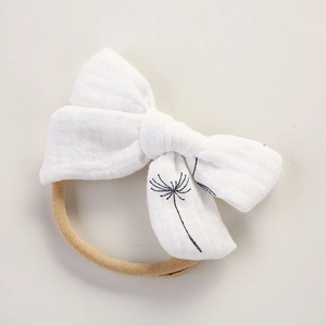 Détail du bandeau bébé en mousseline blanche avec imprimé pissenlit noir et bande élastique