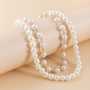 Close-up of stacked pearl necklace with sparkling heart pendant and gold metal chain details