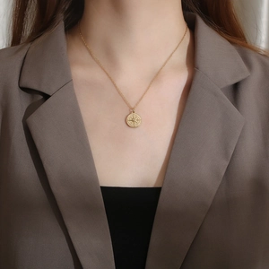 Detail view of a gold vintage compass pendant necklace on a model with a brown blazer