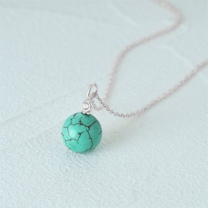Macro detail of spherical turquoise pendant with s925 silver chain and diamond accent