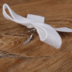 Close-up of a white felt Christmas tree bow ornament with a silver twist tie detail
