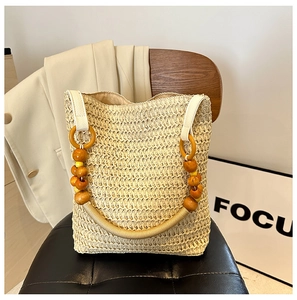 Detail of beaded wooden handle and woven straw texture on beige summer tote bag