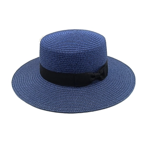 Close-up of deep blue boater hat with woven texture and black grosgrain ribbon bow