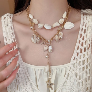Close-up of bohemian multilayer necklace with seashells, starfish and pearls