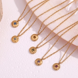 Detail shot of 18K gold plated birthstone pendants with colorful zircon on stone surface
