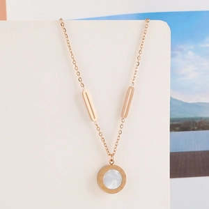 Detailed close-up of rose gold necklace featuring a Roman numeral ring with white shell inlay