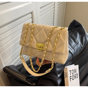 Detail of beige quilted leather crossbody bag featuring gold chain and turn-lock closure
