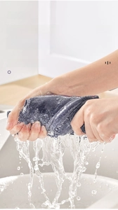 Vue macro d'un chiffon microfibre violet essoré dans un évier avec éclaboussures d'eau