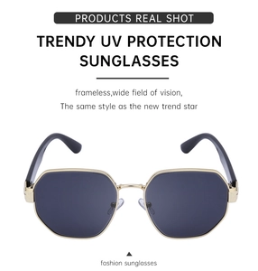 Close-up of trendy polygon sunglasses with gold metal frame and dark grey UV lenses