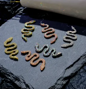 Macro shot of snake-shaped zircon nail art charms in gold, silver, and rose gold finishes