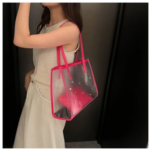 Detail of transparent PVC tote bag with rose pink straps and colorful rhinestone accents