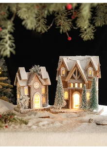 Detail of wooden Christmas cottage with LED lights and faux snow on black background