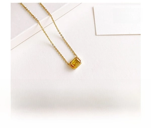 Detalle de colgante de gema amarilla corte esmeralda en cadena de titanio chapada en oro