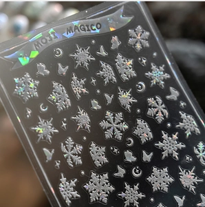 Macro shot of holographic silver snowflake and butterfly nail art stickers