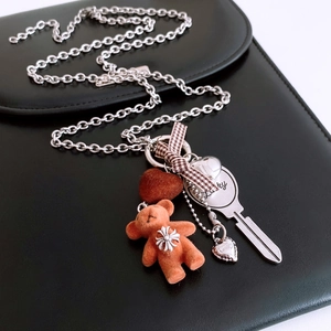 Close-up of titanium steel necklace with flocking bear, bow and Lucky key pendant