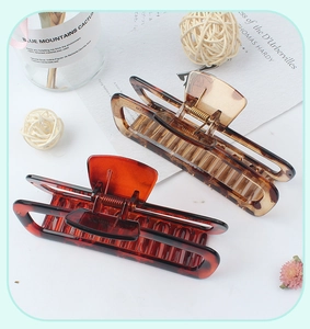 Close-up of two large hollow rectangular leopard print hair claws with gold springs
