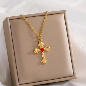 Detail of gold cross pendant with red heart center on satin inside a gift box
