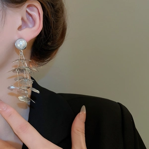 Detail of silver hollow flower earrings with layered ginkgo leaf tassels and pearls